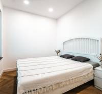 A bedroom in a family house with a wood-patterned floor, white walls, and a bed.