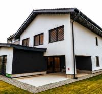 A family house in Stará Ľubovňa with a white facade, a terrace, and sloping terrain.