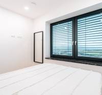 A bedroom in a family house with a large window and a mirror.