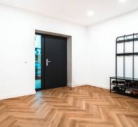 Entrance hall in a family house with a wooden decor floor, shoe rack, and coat hooks.