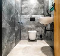 A bathroom in a family house with marble walls and white sanitary fixtures.