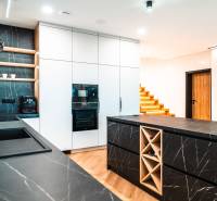 A kitchen in a family house with dark countertops and a wooden decor floor.