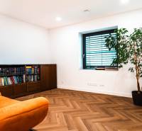 A room in a family house with a comfortable armchair, a bookshelf, and a wooden decor floor.