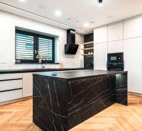 A kitchen in a family house with a marble island and a wood-patterned floor.