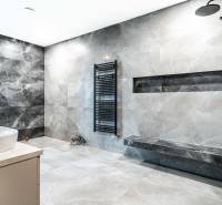 A bathroom in a family house with a black shower enclosure and gray wall tiles.