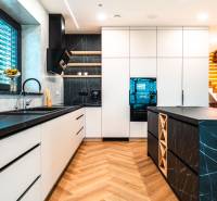 A kitchen in a family house with a wooden decor floor and black countertops.