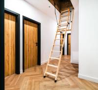 A wooden decor floor in the hallway of a family house with a pull-out staircase.