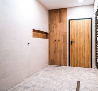 A bathroom in a family house with a wooden decor floor and large-format tiles.
