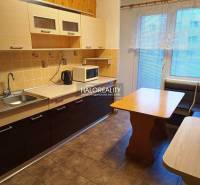 A kitchen in a 3-room apartment with light cabinets, a corner bench, and a floor with a wood decor.