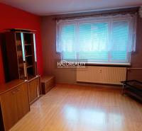 A room with a wooden decor floor, red walls, and furniture in a 3-room apartment.