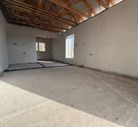Interior of a family house with a concrete floor, wooden beams, and electrical wiring.