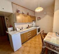 A kitchen in a 2-room apartment with a wooden kitchen unit and a dining table.