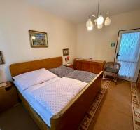 Bedroom in a 2-room apartment with an upholstered bed, carpeted floor, and decorative paintings.