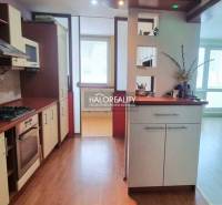 A kitchen in a studio apartment with a wood-patterned floor and a light interior.