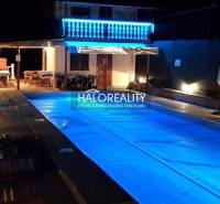 A nighttime atmosphere at the cottage in Byšte with an illuminated pool and seating on the terrace.