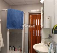 A bathroom with a shower in the cottage, equipped with a sink and storage cabinets.