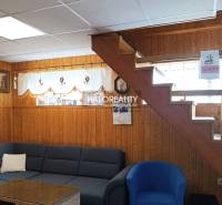Interior of a cabin with wooden paneling, stairs, a sofa, and decorations on the walls.