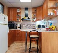 A kitchen in a cabin with wooden decor, a bar counter, and appliances.
