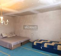 A bedroom in a family house with a bed, mattress, light fixture, and simple furniture.