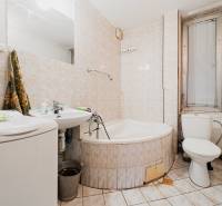 Bathroom with a bathtub, sink, and washing machine in a family house.