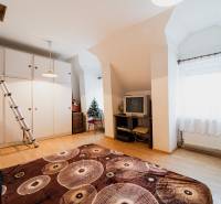 A room in a family house with a wooden decor floor, a television, and a wardrobe.