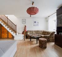 Living room in a family house with a wooden staircase, sofa, cabinet, and floor with a wooden decor.