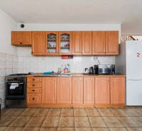 A kitchen in a family house with wooden cabinets, a white refrigerator, and wooden decor flooring.