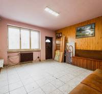 Interior of a family house with tiling, wooden paneling, and a sofa by the window.