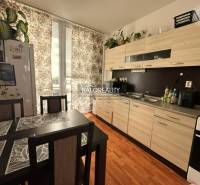 The kitchen in a 3-room apartment with a wooden decor floor, a dining table, and curtains.