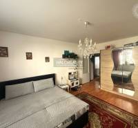 A bedroom with a chandelier and a wardrobe, a floor with a wooden decor in a 3-room apartment.