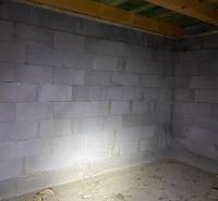 A raw room in a cabin with concrete walls and a wooden ceiling.