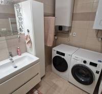 A bathroom with a sink, washing machine, and dryer in a 3-room apartment.