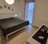 Bedroom in a 3-room apartment with wood-patterned flooring and wall decoration.