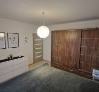 Bedroom in a 3-room apartment with wood-patterned flooring, white furniture, wall decorations.