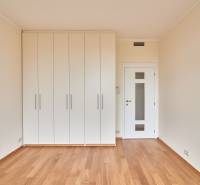 A bright room with wood-patterned flooring and white built-in wardrobes in a 3-room apartment.