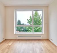 A room with a bright window, white walls, and a floor with a wood decor in a 3-room apartment.