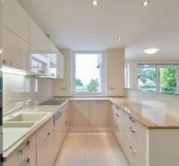 A kitchen in a 3-room apartment with a large window, white cabinets, and a glossy countertop.