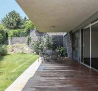 A terrace with a wooden decor floor, garden seating, and greenery by a 3-room apartment.