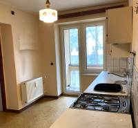 A kitchen in a 2-room apartment with a gas stove and a wooden decor floor.