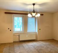 A room in a two-room apartment with a wooden decor floor and a hanging chandelier.
