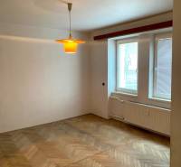 A room in a 2-room apartment with a wood-decor floor and a window with blinds.