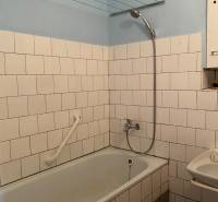 Bathroom in a 2-room apartment with a bathtub, white tiles, and a showerhead.