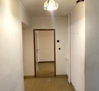 A hallway with tiles and a chandelier leading to a room in a 2-bedroom apartment.