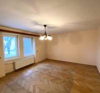 A room in a 2-room apartment with a wooden decor floor and a central chandelier.