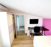 A room in a family house with a wooden decor floor, a work desk, and air conditioning.