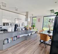 A kitchen in a family house with a wooden decor floor, a dining table, plenty of light.