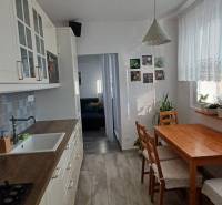 A kitchen in a 3-room apartment with a wooden decor, a dining table, and plants.