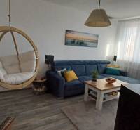 Living room with a swing chair, sofa, and wooden decor flooring, 3-room apartment.