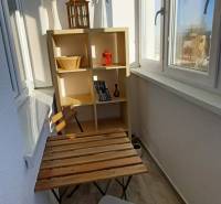 Balcony of a 3-room apartment with furniture and a wooden table, floor with wooden decor.