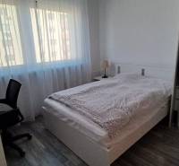 Bedroom in a 3-room apartment with a bed, a desk, and a floor with a wooden decor.